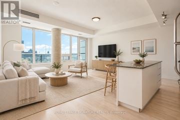Toronto (Niagara) condo for rent - A well-lit, spacious living room with a large window, a sofa, a coffee table, and a kitchen area.