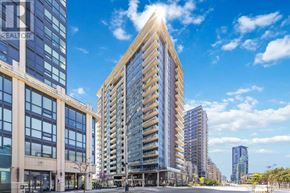 Toronto (Niagara) condo for rent - A tall, modern building with a glass facade stands in the foreground of a city street.