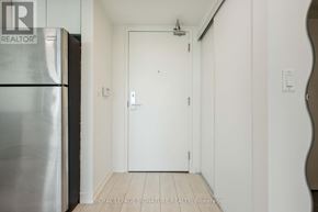 Toronto (Niagara) condo for rent - A white door is in a hallway with a refrigerator on the left.