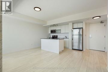 Toronto (Niagara) condo for rent - A kitchen with white cabinets and a refrigerator in a room with wooden flooring.