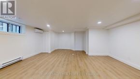 Toronto (Lawrence Park South) multi-family for rent - A spacious room with wooden flooring and white walls, with a window on the left side.