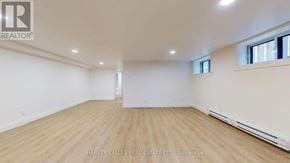 Toronto (Lawrence Park South) multi-family for rent - A spacious room with wooden flooring and white walls, with a window on the right side.