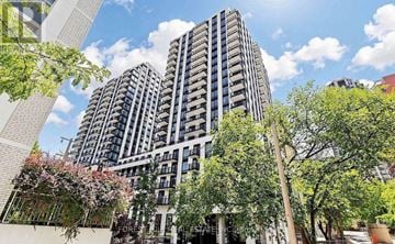 Toronto (Forest Hill South) condo for rent - A modern building with a lot of windows and balconies is surrounded by trees and plants.