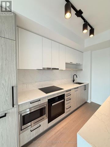 Toronto (Forest Hill South) condo for rent - A modern kitchen with white cabinets and stainless steel appliances.