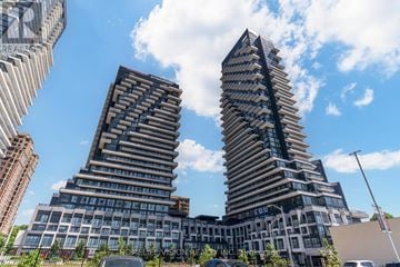 Toronto (Banbury-Don Mills) condo for rent - Two tall buildings with balconies on each floor are seen against a blue sky.