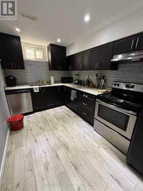 Toronto (Guildwood) apartment for rent - A modern kitchen with black cabinets and a wooden floor.