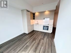 Vaughan (Vaughan Corporate Centre) condo for rent - A kitchen with white cabinets and a wooden floor.