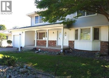 Windsor apartment for rent - A house with a white front porch and a tree in front.