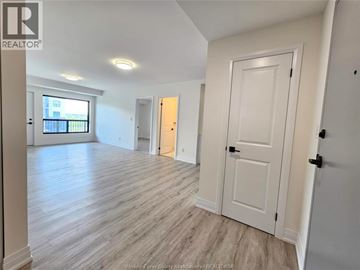 Windsor condo for rent - A spacious room with wooden flooring and white walls.