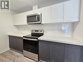 Windsor condo for rent - A kitchen with a stove top oven and microwave.