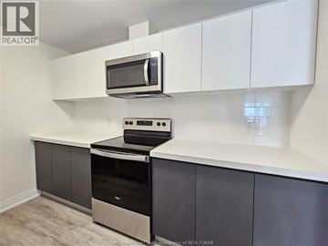 Windsor condo for rent - A kitchen with a stove top oven and microwave.