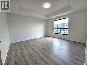 Windsor condo for rent - A spacious room with a large window and wooden flooring.