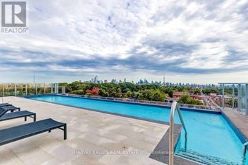 Toronto (Casa Loma) condo for rent - A pool with a bench and a city view in the background.
