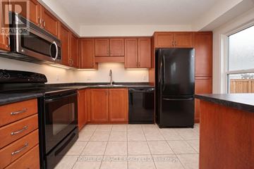 Kitchener townhouse for rent - A kitchen with wooden cabinets and black appliances.