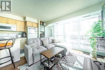 Toronto (Waterfront Communities) condo for rent - A well-lit living room with a grey couch and a wooden coffee table.
