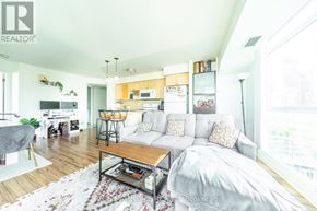 Toronto (Waterfront Communities) condo for rent - A living room with a couch, coffee table, and kitchen area in the background.