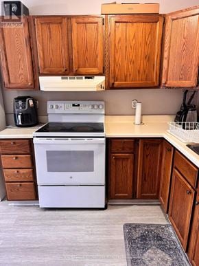 Orangeville townhouse for rent - A white oven and stove top are in a kitchen with wooden cabinets.