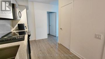 Toronto (Clanton Park) condo for rent - A kitchen area with a stove top oven and a doorway leading to another room.