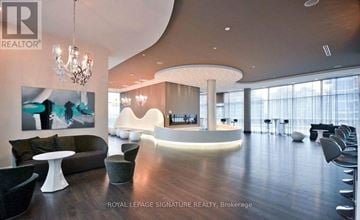Toronto (Mimico) condo for rent - A modern living room with a curved white wall and a chandelier.