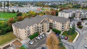 Oakville (Ga Glen Abbey) condo for rent - A large apartment complex with a parking lot in front.
