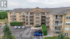 Oakville (Ga Glen Abbey) condo for rent - A large apartment complex with a parking lot in front.