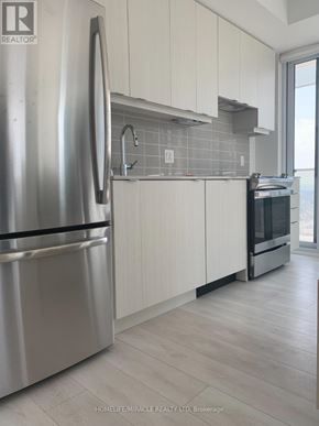 Mississauga (City Centre) condo for rent - A modern kitchen with a stainless steel refrigerator and white cabinets.