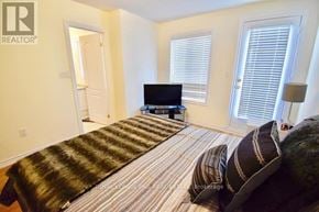 Brampton (Heart Lake East) townhouse for rent - A bedroom with a bed, a television, and a window with blinds.