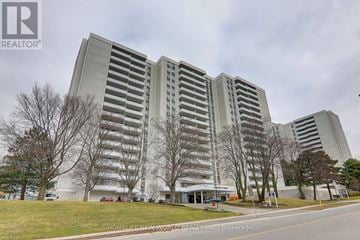Toronto (Henry Farm) condo for rent - A large, modern building with a glass facade is the main focus of the image.