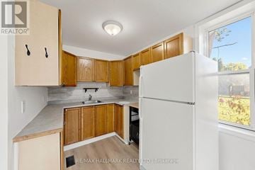 Kawartha Lakes (Lindsay) triplex for rent - A kitchen with wooden cabinets and a white refrigerator.