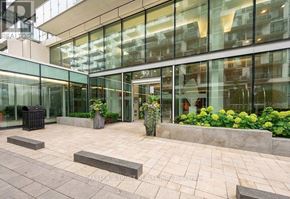 Toronto (Waterfront Communities) condo for rent - A modern building with glass walls and a stone walkway in front.