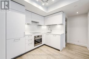 Toronto (Thorncliffe Park) condo for rent - A white kitchen with a refrigerator, sink, and cabinets.