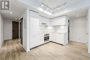 Toronto (Thorncliffe Park) condo for rent - A well-lit, spacious kitchen with white cabinets and a wooden floor.