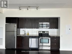 Toronto (South Parkdale) condo for rent - A modern kitchen with stainless steel appliances and dark wood cabinets.