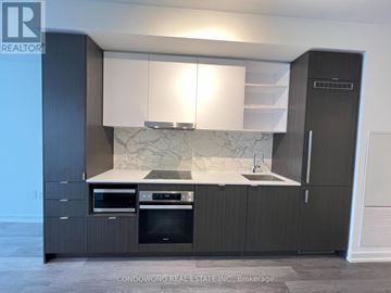 Toronto (Waterfront Communities) condo for rent - A modern kitchen with dark wood cabinets and a marble backsplash.