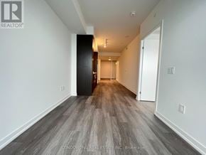 Toronto (Waterfront Communities) condo for rent - A long hallway with wood flooring and white walls.