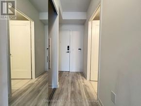 Toronto (Waterfront Communities) condo for rent - A hallway with white walls and wood flooring.