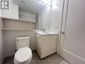 Toronto (Waterfront Communities) condo for rent - A white toilet sits in a small bathroom with a sink and medicine cabinet.