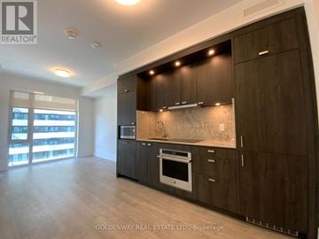 Toronto (Waterfront Communities) condo for rent - A modern kitchen with dark wood cabinets and a marble backsplash.