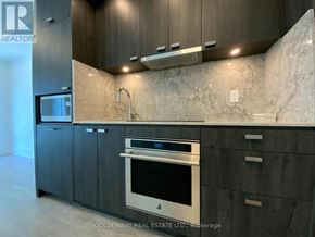 Toronto (Waterfront Communities) condo for rent - A modern kitchen with dark wood cabinets and a marble backsplash.