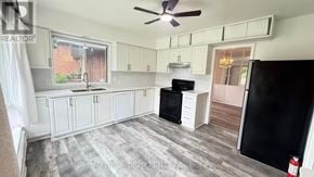 Toronto (Willowdale West) apartment for rent - A kitchen with a black refrigerator, white cabinets, and a ceiling fan.