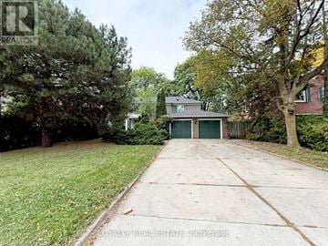 Markham (Bayview Glen) apartment for rent - A house with a garage is surrounded by trees and grass.