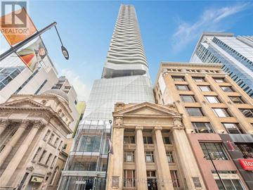 Toronto (Church-Yonge Corridor) condo for rent - A tall building with a glass facade stands in front of a row of other buildings.