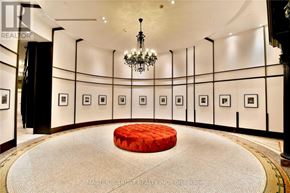 Toronto (Church-Yonge Corridor) condo for rent - A room with a chandelier, picture frames on the wall and a red ottoman in the middle.