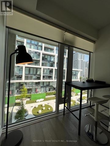 Toronto (Mount Pleasant West) condo for rent - A black lamp stands on a table in a room with a view of a courtyard.