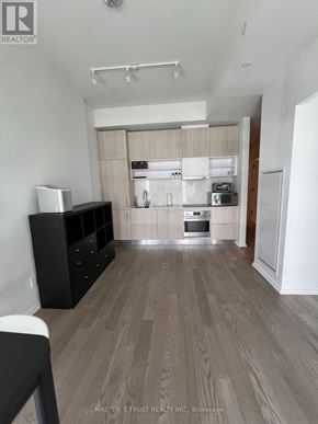 Toronto (Mount Pleasant West) condo for rent - A kitchen with a white fridge, black cabinetry, and a wooden floor.