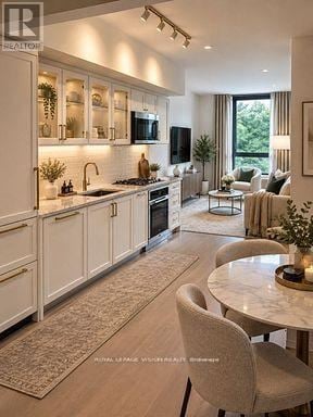 Toronto (Englemount-Lawrence) condo for rent - A modern kitchen with white cabinets and a dining area with a round table and chairs.