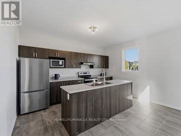 Ottawa apartment for rent - A modern kitchen with a refrigerator, microwave, oven, sink, and cabinets.