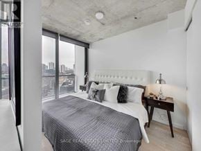 Toronto (Waterfront Communities) condo for rent - A bedroom with a large bed and a city view through the window.
