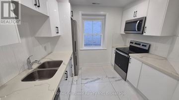 Brantford multi-family for rent - A kitchen with white cabinets and a black oven.