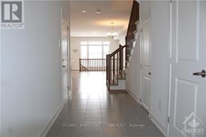 Ottawa townhouse for rent - A hallway with white walls and a tiled floor leads to a bright room with a window.